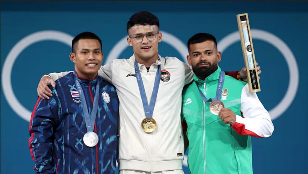 Rizki Juniansyah (tengah), atlet angkat besi Indonesia peraih emas Olimpaide 2024 (olympics.com)