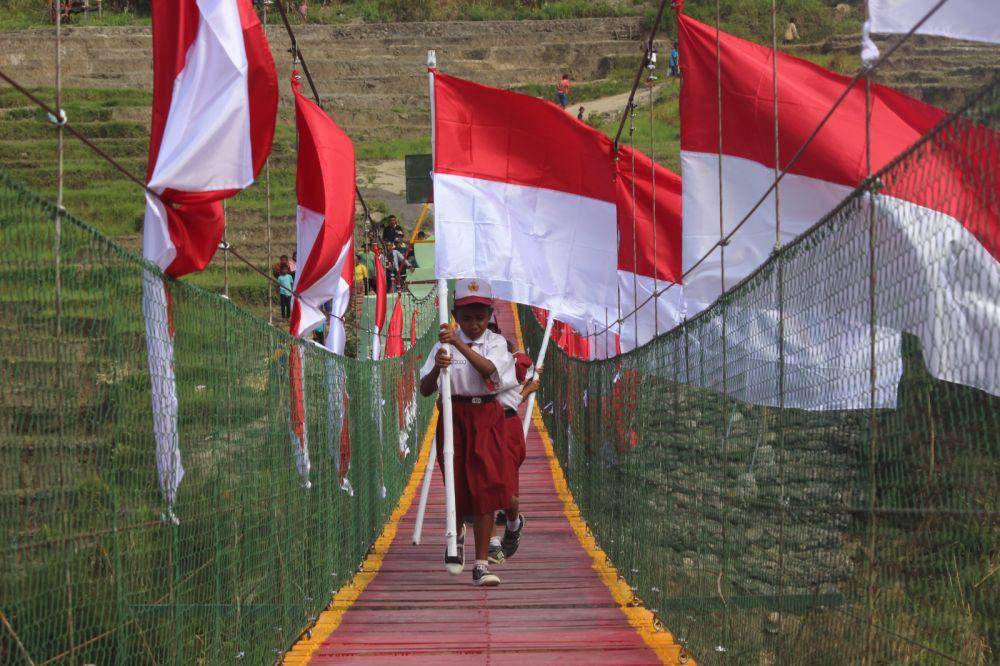Anak-anak di NTT melintasi sungai Noebesi menggunakan jembatan gantung yang sudah rampung dibangun. (Dok. Satgas Pamtas RI-RDTL)