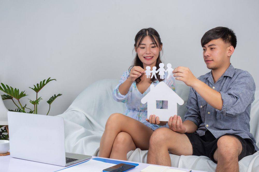 Ilustrasi pasangan memegang rumah kertas di sofa (freepik.com/jcomp)