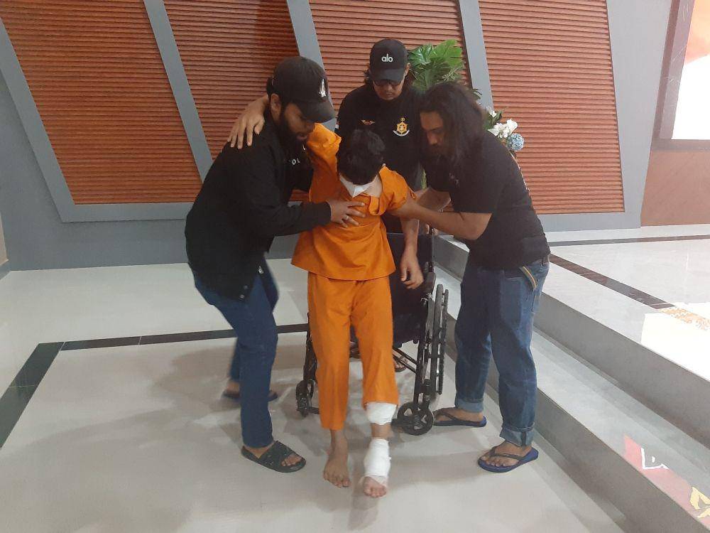 Febri Irawan, perampok gerai BRI Link yang ditangkap tim gabungan Polda Riau dan Polres Pelalawan, tampak kesakitan saat hendak didudukkan di kursi roda (IDN Times/ Fanny Rizano)