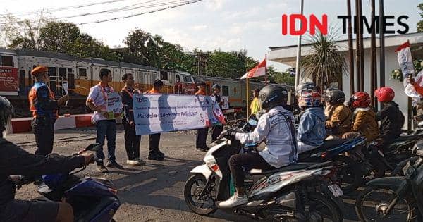 Dengan latar belakang kereta yang melintas pengguna diingatkan ketika akan melewati pintu lintasan kereta api, Jumat (16/8/2025).(IDN Times/Cokie Sutrisno)