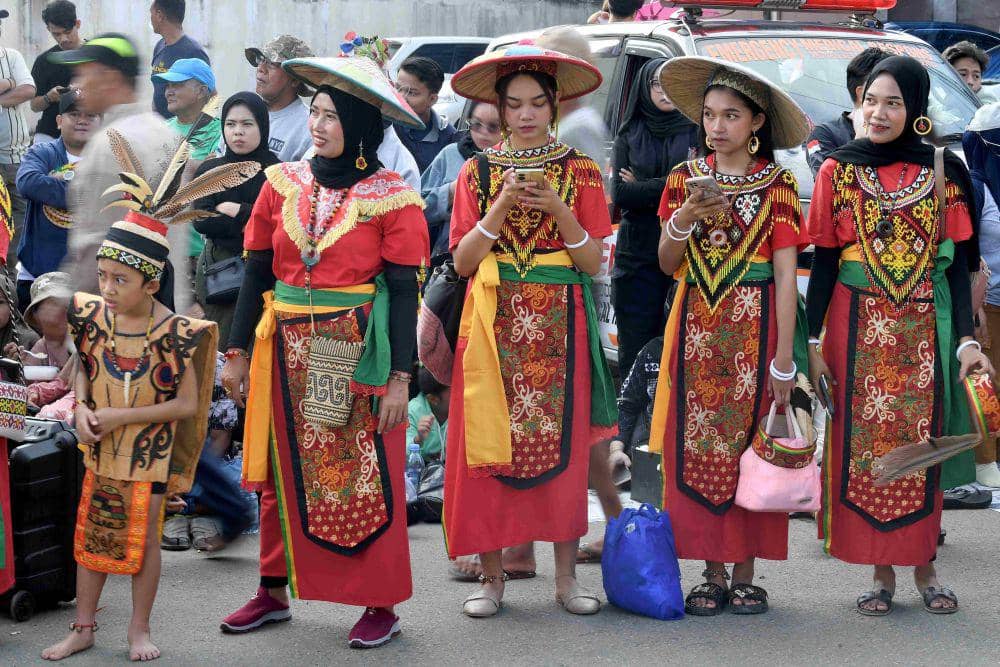 Warga mengenakan pakaian khas Suku Dayak menyaksikan pawai pembangunan dan karnaval budaya nusantara di Samarinda, Kalimantan Timur, Minggu (18/8/2024).   ANTARA FOTO/M Risyal Hidayat/Spt.