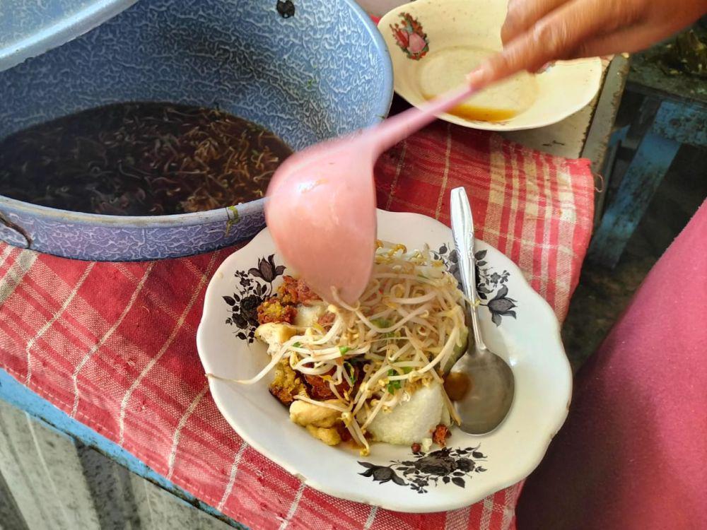 Proses menuangkan kuah lontong balap. IDN Times/Talita Hariyanto