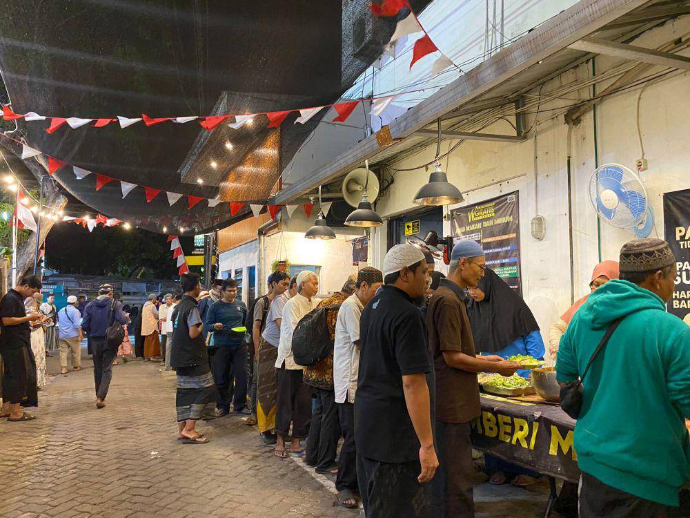 Para pengunjung dan warga sedang mengambil makanan yang disediakan (IDN Times/Ryzka Tiara)