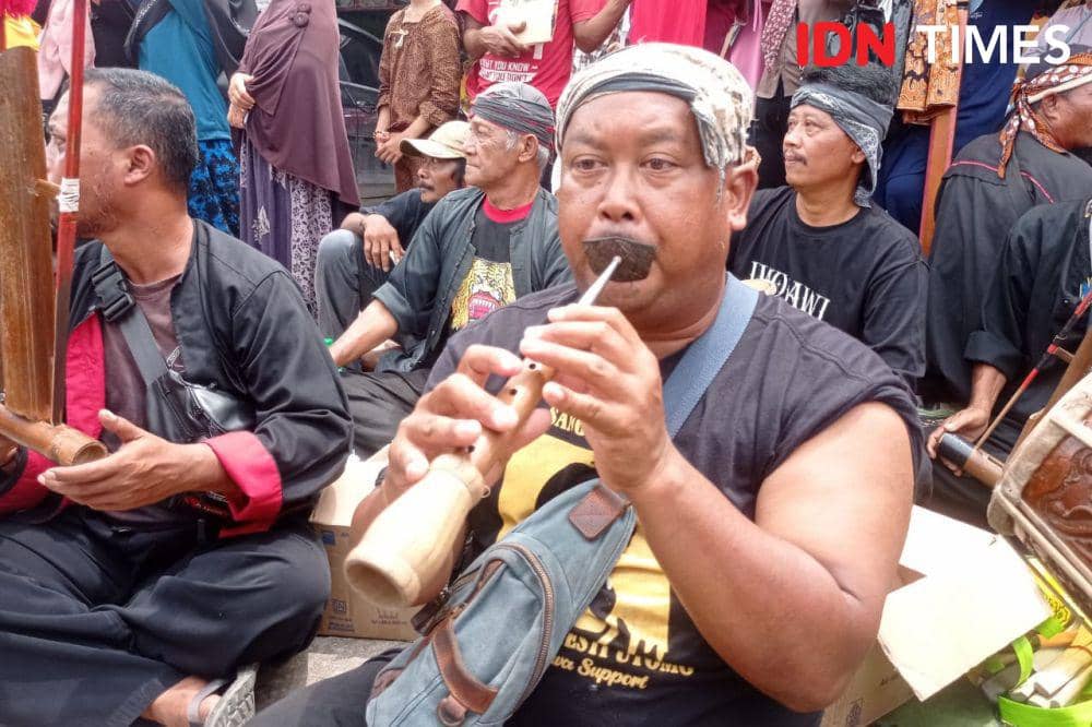 Seorang pria memainkan alat musik tiup untuk iringi tarian Reog (IDN Times/Putra Gema Pamungkas)
