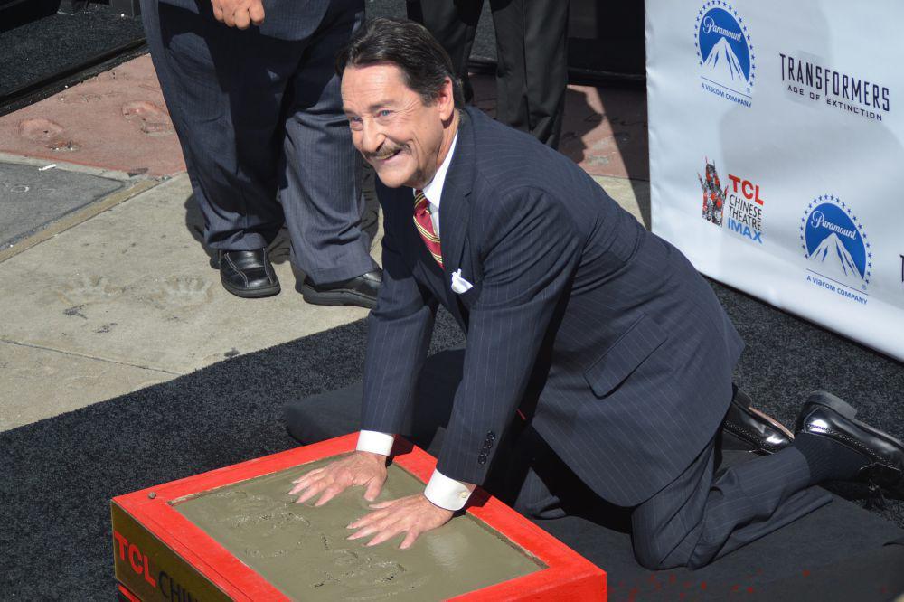 Aktor Peter Cullen meletakkan cetakan tangannya di semen basah di Upacara Cetakan Tangan di Los Angeles. (commons.wikimedia.org/Media TV)