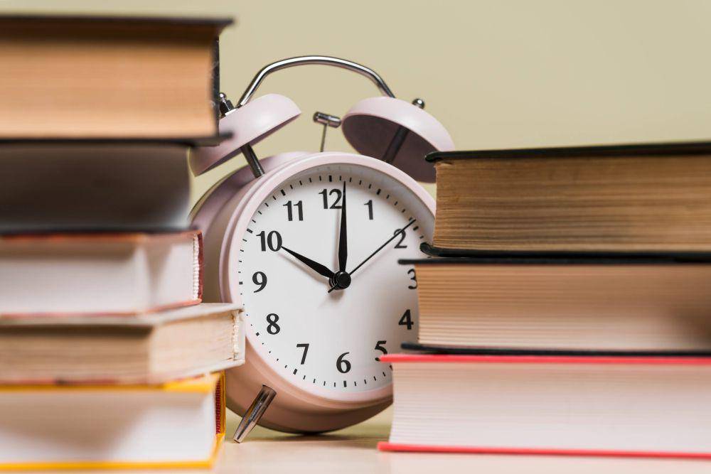 Tumpukan buku dan jam. Freepik/freepik