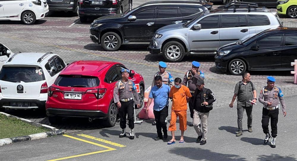 Bripka AS (baju tahanan oranye) saat digiring pihak kepolisian untuk diekspose (IDN Times/ Fanny Rizano)