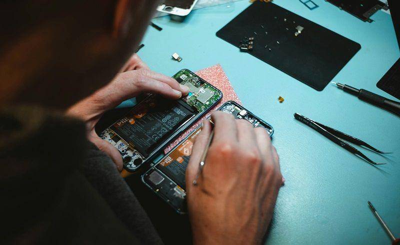 ilustrasi tukang servis HP memperbaiki ponsel mati total (unsplash.com/Kilian Seiler)