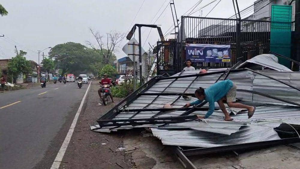 Warga membersihan rumahnya yang rusak akibat disapu angin dan hujan. IDN Times/ Riyanto.