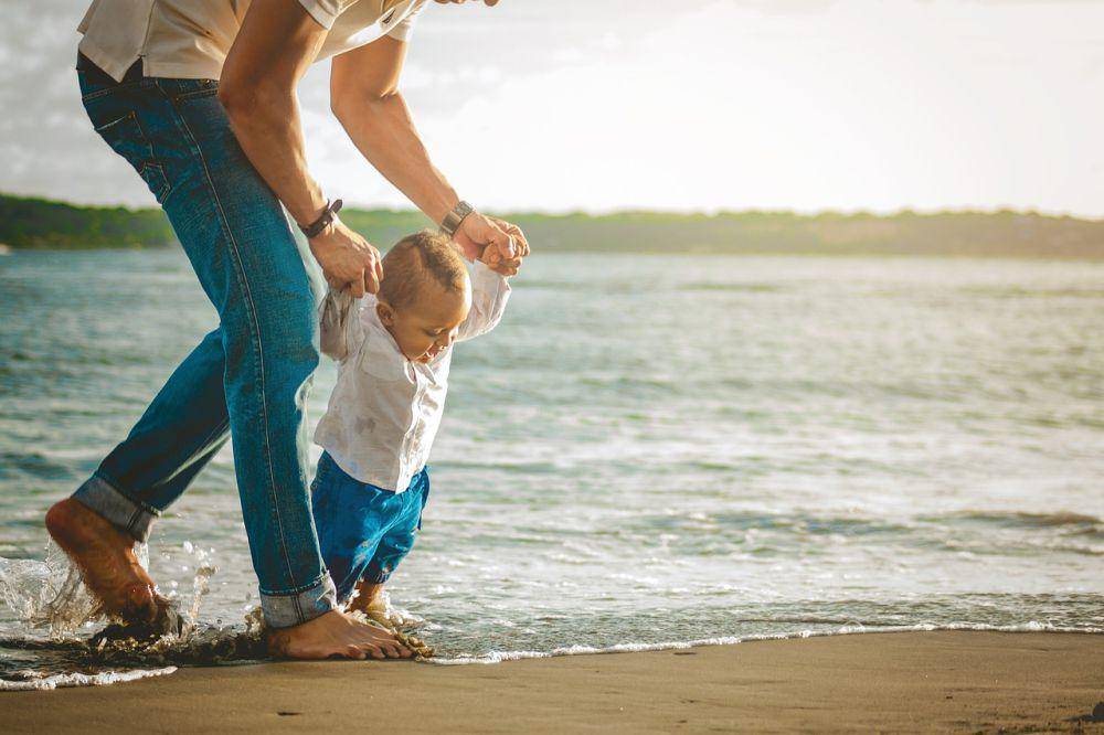 Seorang balita sedang berjalan di atas pasir pantai bersama ayahnya. (Pixabay.com/jump1987)