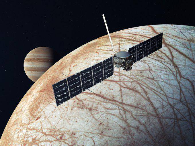 Ilustrasi yang menggambarkan wahana antariksa Europa Clipper di atas bulan Europa, dengan Jupiter menjadi latar belakang. (x.com/NASA)
