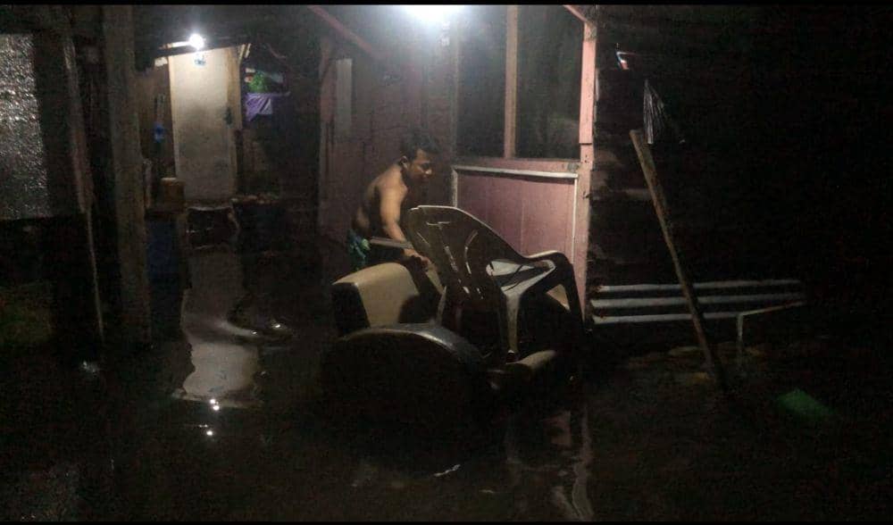 Seorang warga menyelamatkan sofanya yang hampir terseret air (Foto: IDN Times/Halbert Caniago)