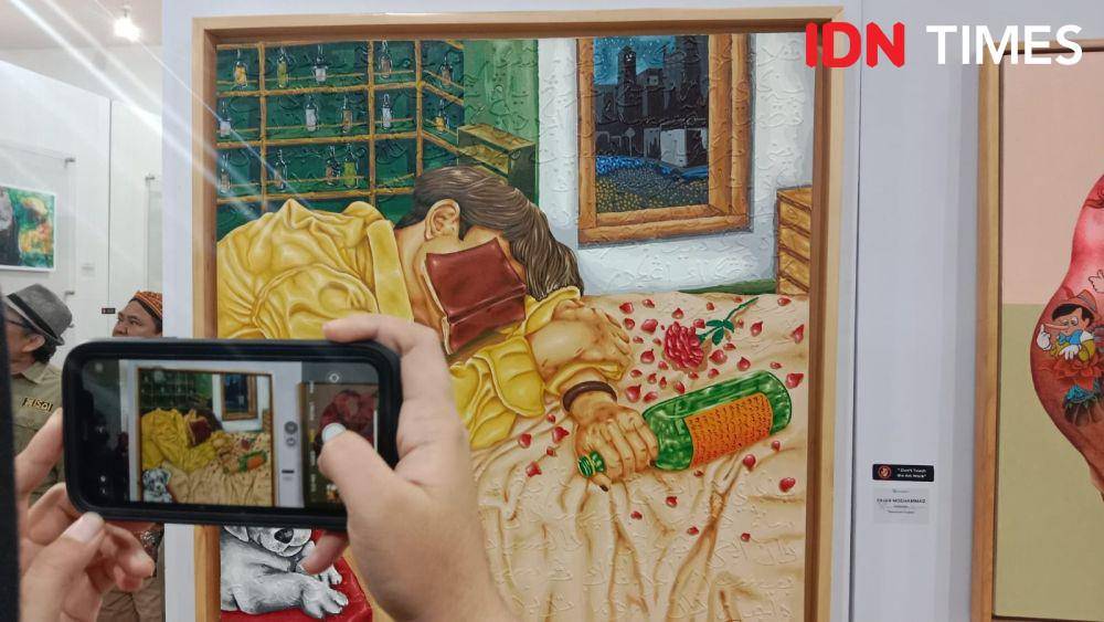 Lukisan yang menarasikan seorang pria memegang botol dengan wajah ditutupi buku ini mencuri perhatian dalam pameran di Walisongo Center Semarang. (IDN Times/Fariz Fardianto)