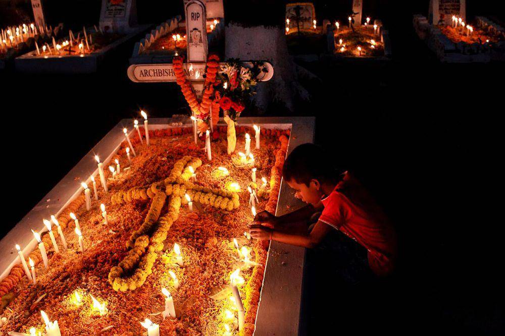 Seorang anak sedang memanjatkan doa di makam anggota keluarganya untuk memperingati Hari Raya Arwah atau All Souls' Day di Pemakaman Suci di Chattogram, Bangladesh. (commons.wikimedia.org/MuhammadAmdadHossain)