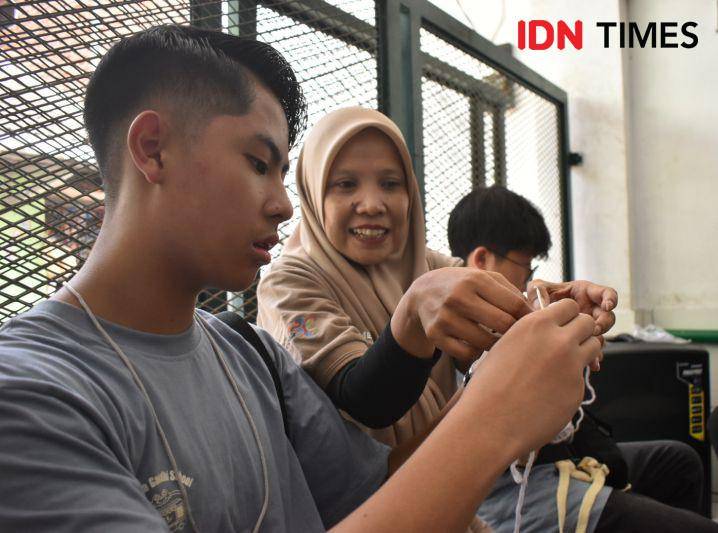 Mentor dari Komunitas Merakit, Erlina (tengah), sedang mengajarkan siswa dari SMP Mahatma Gandhi, Jakarta, membuat gelang dari benang rajut. IDN Times/Debbie Sutrisno