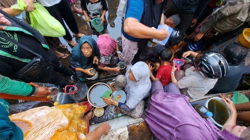 Warga berebut minyak goreng yang tumpah dari truk kontainer terbalik di depan kampus UNM Jl AP Pettarani Makassar, Kamis (24/10/2024). (IDN Times/Darsil Yahya)