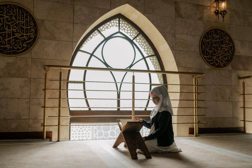 Ilustrasi seorang gadis kecil yang sedang membaca Al-Qur'an. (pexels.com/Alena Darmel)