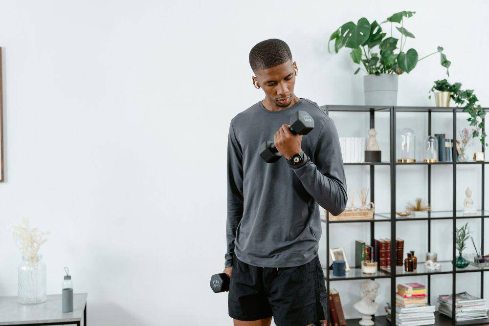ilustrasi pria menggunakan dumbbell (pexels.com/MART PRODUCTION)