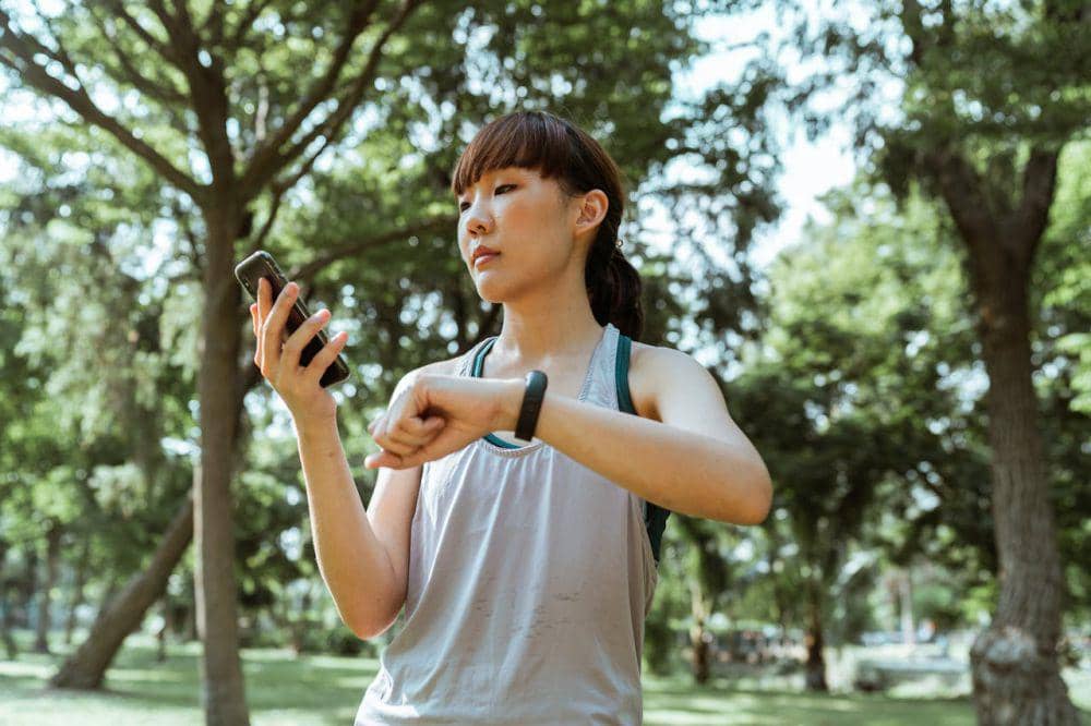 Seorang perempuan sedang melihat fitness tracker yang dipakainya saat berolahraga.