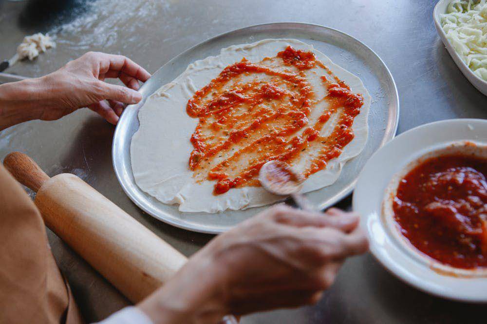ilustrasi mengoles saus pada adonan pizza (pexels.com/Antonius Ferret)