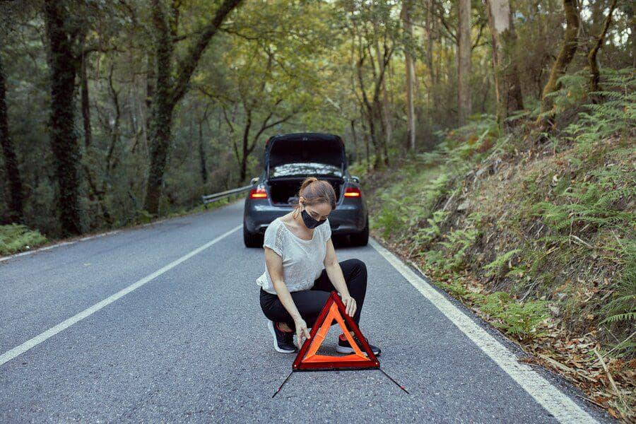 ilustrasi seorang wanita meletakkan segitiga pengaman di jalan (freepik.com/miguelsoutullo)