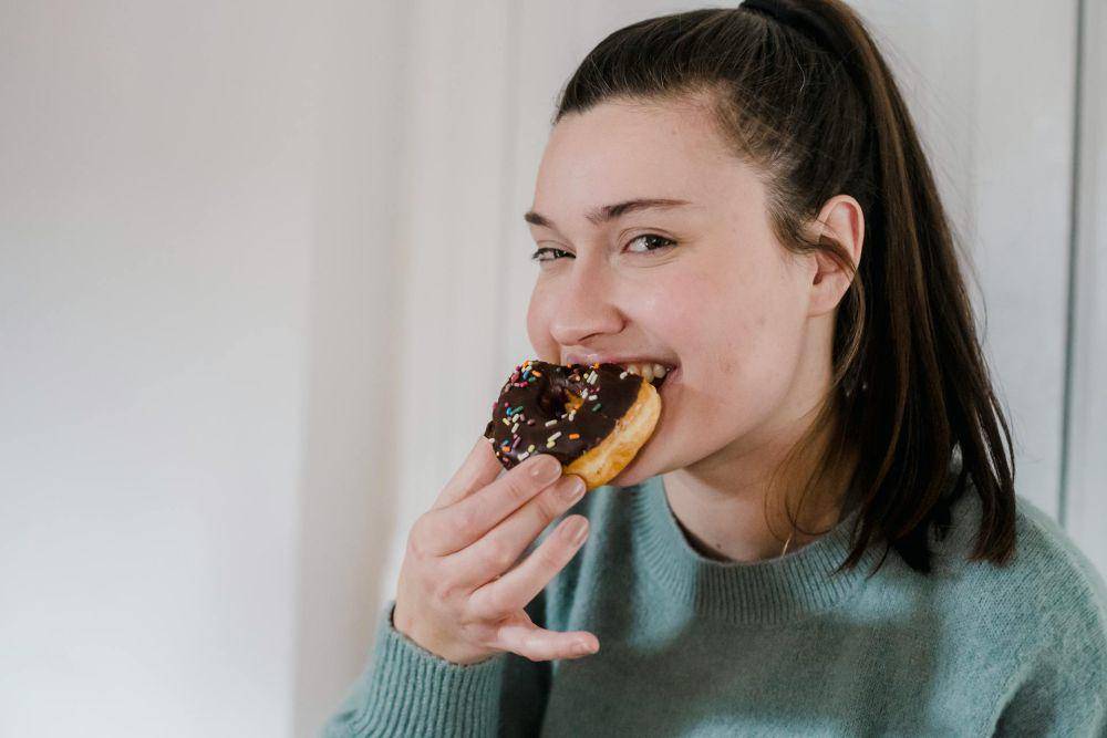 ilustrasi perempuan sedang makan donat (pexels.com/Tim Samuel)