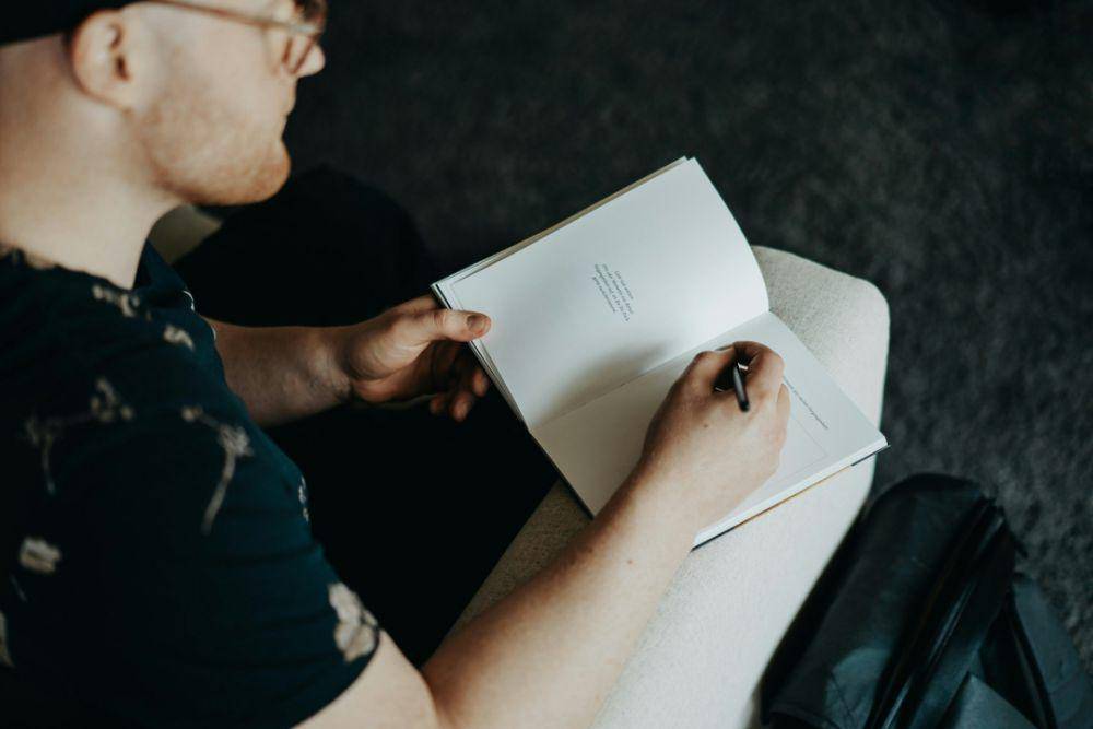 Seorang laki-laki sedang menulis jurnal (unsplash.com/Finde Zukunft)