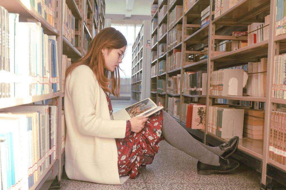 ilustrasi seorang perempuan membaca di perpustakaan (pexels.com/Maggie Zhan)