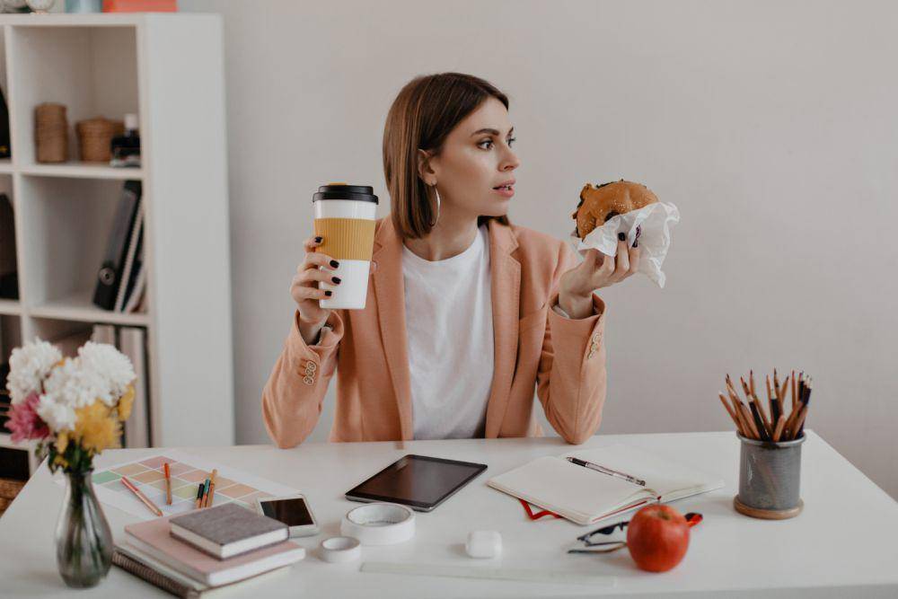 Ilustrasi wanita makan di ruang kerja (freepik.com/lookstudio)