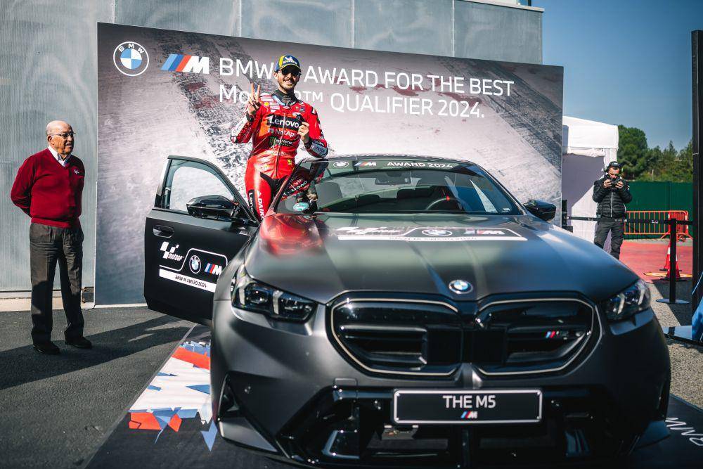 Francesco Bagnaia berfoto dengan mobil BMW M5 selepas sesi kualifikasi GP Solidaritas 2024. (press.bmwgroup.com)