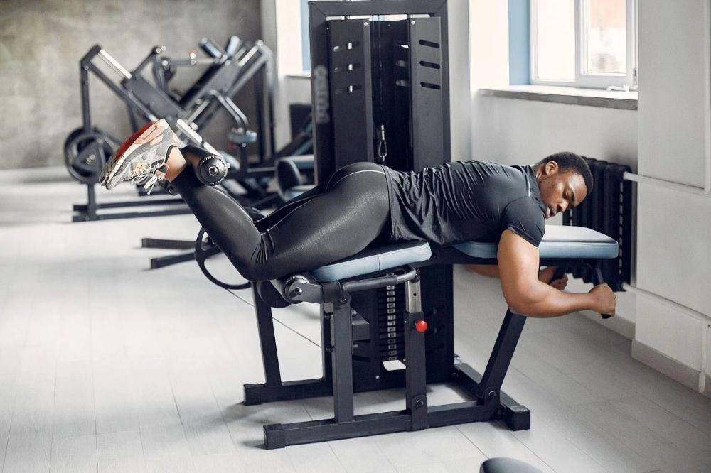 ilustrasi laki-laki sedang menggunakan leg curl machine di gym (dok/prowolf.in)