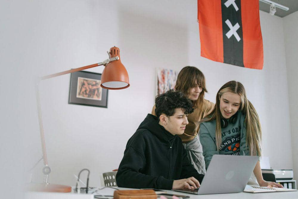 Ilustrasi tiga pemuda berkumpul di depan laptop. (pexels.com/Ivan Samkov)