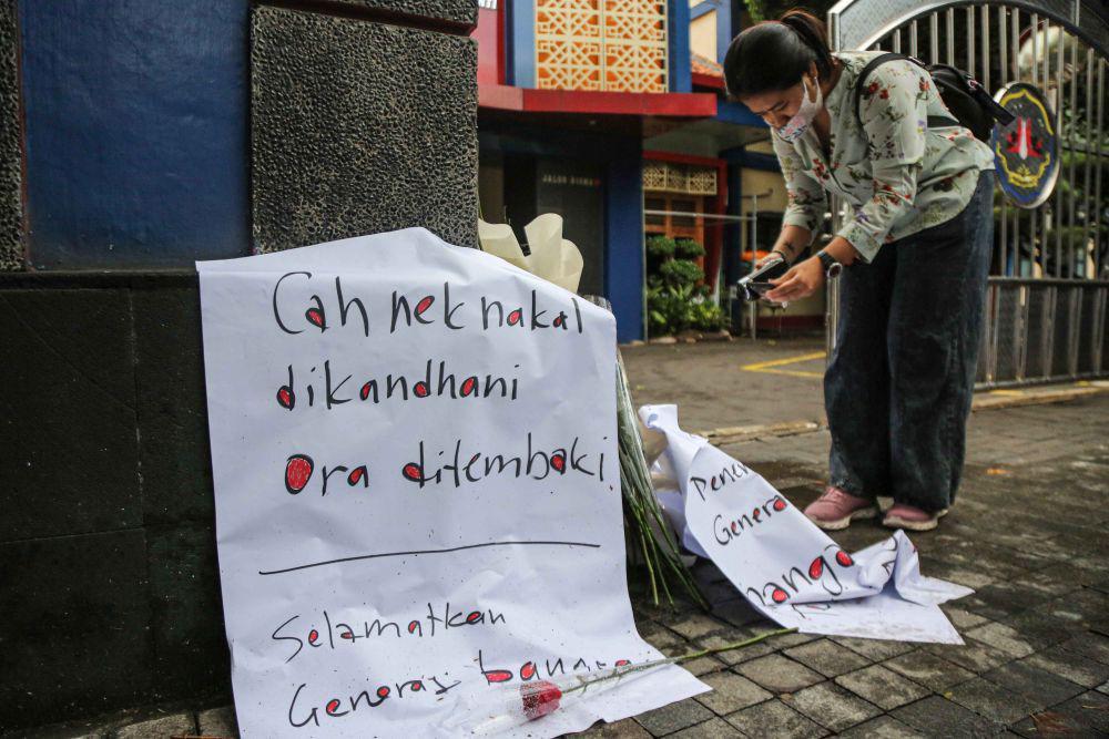 Seorang wartawan mengambil gambar bunga-bunga yang diletakkan untuk dukungan dan doa kepada siswa yang meninggal dunia diduga akibat ditembak oknum polisi di depan SMKN 4 Semarang, Semarang, Jawa Tengah, Selasa (26/11/2024). (ANTARA FOTO/Makna Zaezar)