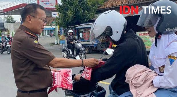 Momen pengendara motor yang mendapat kaos Stop Korupsi dar Kajari Banyumas Adung Sutranggono, Senin (9/12/2024).(IDN Times/Cokie Sutrisno)