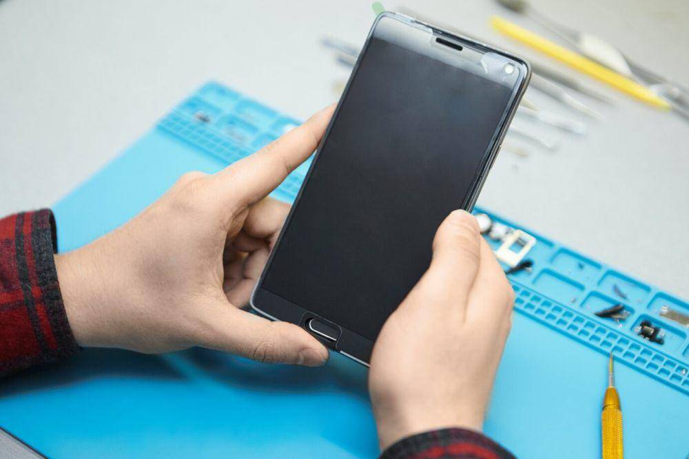 ilustrasi pengguna mengecek pemasangan layar HP dengan tempered glass (freepik.com/karlyukav)