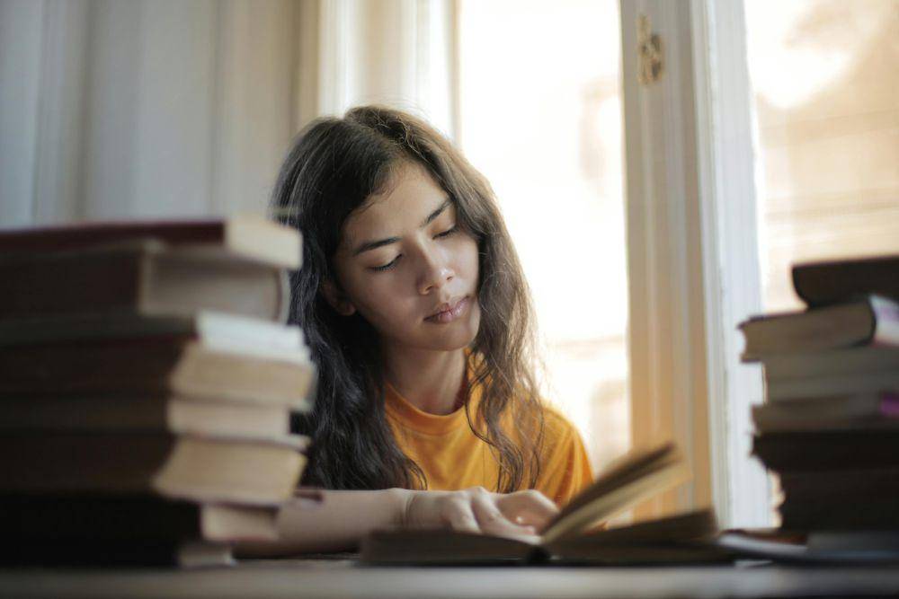 ilustrasi foto seorang wanita sedang membaca buku. (pexels.com/Andrea Piacquadio)