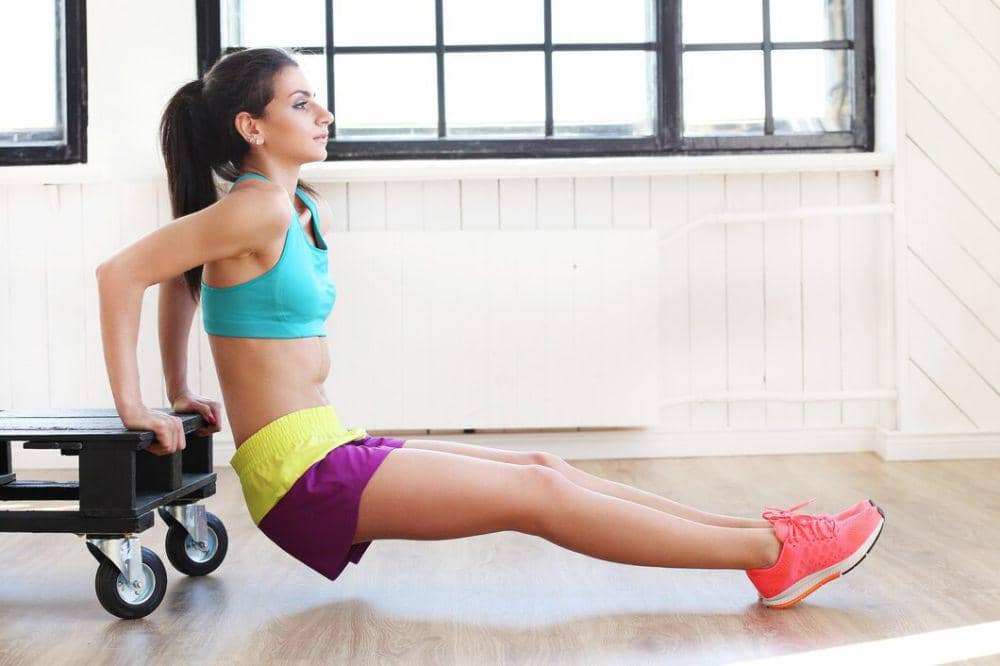 Seorang perempuan melakukan latihan triceps dips.