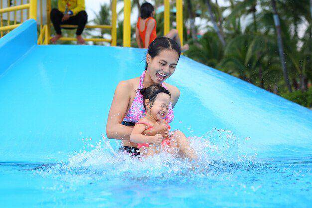 Ibu dan anak bermain seluncuran kolam. Freepik.