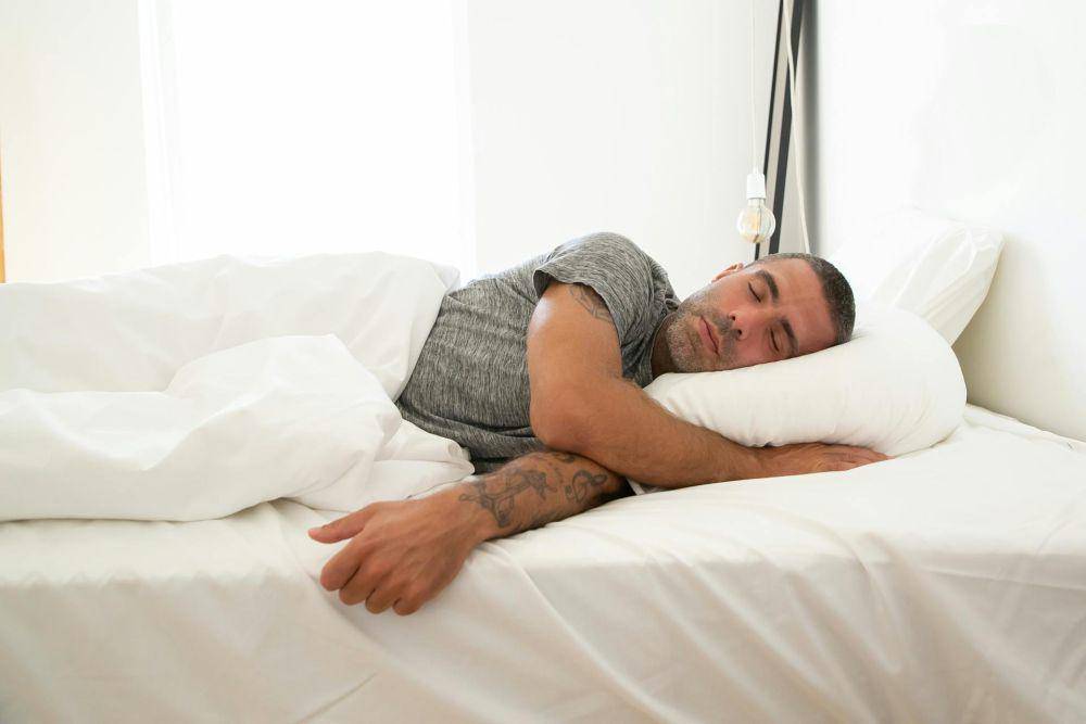 Foto pria yang sedang tidur di kasur putih. (pexels.com/Kampus Production)
