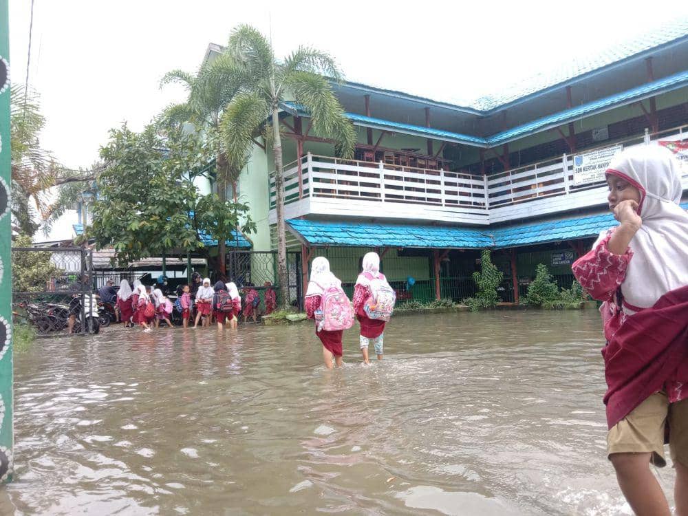 Aktivitas siswa SD di Banjarmasin saat banjir rob dan hujan.