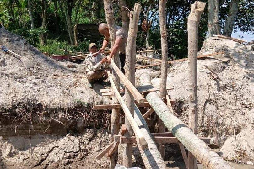 Bhabinkamtibmas Desa Unjur Kecamatan Simanindo, Samosir, membangun jembatan kayu di lokasi di rumah Darma yang viral karena dikelilingi parit usai digali salah satu kerabatnya (dok. Humas Polres Samosir)