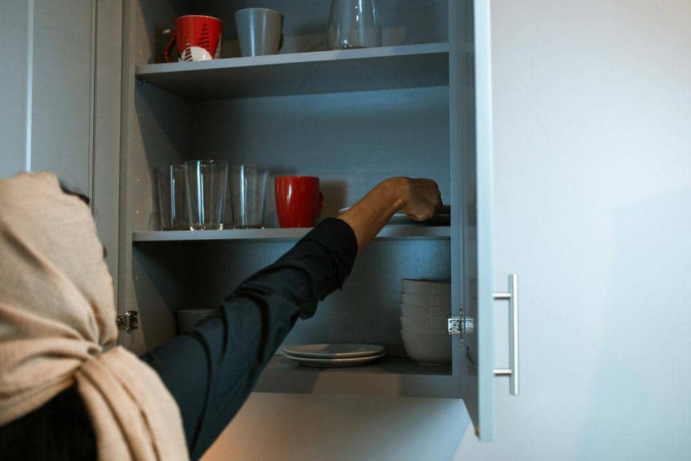 ilustrasi seseorang menyimpan piring di lemari dapur 