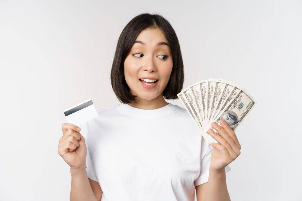 Ilustrasi perempuan memegang kartu kredit dan uang tunai dolar AS. (Freepik / benzoix)