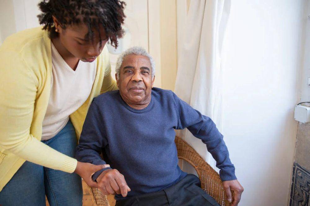Seorang caregiver membantu lansia duduk.