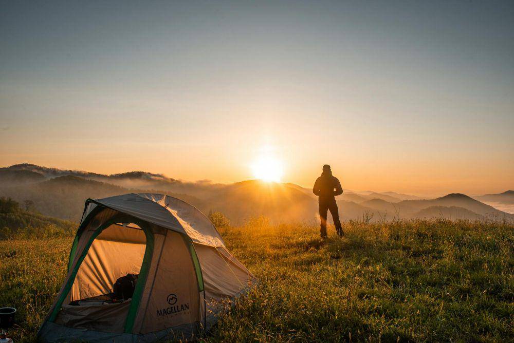 Ilustrasi pendaki gunung berdiri di samping tenda (pexels.com/iCliford Mervil)