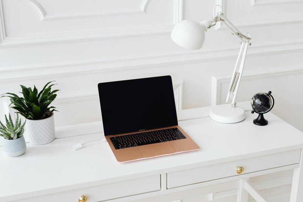 Ilustrasi MacBook pada meja berwarna putih  (pexels.com/Photo By: Kaboompics.com)