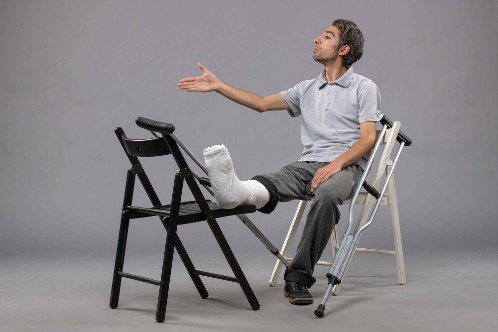 ilustrasi seseorang duduk di kursi dengan kondisi cedera kaki (freepik.com/KamranAydinov)