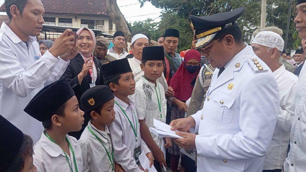 Bupati Lotim, Haerul Warisin saat memberikan santunan kepada anak yatim (IDN Times/Ruhaili)
