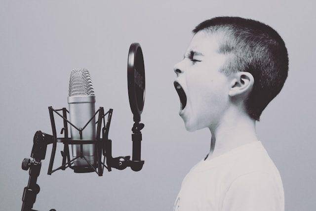 Seorang anak berteriak di depan mikrofon (unsplash.com/@jasonrosewell)